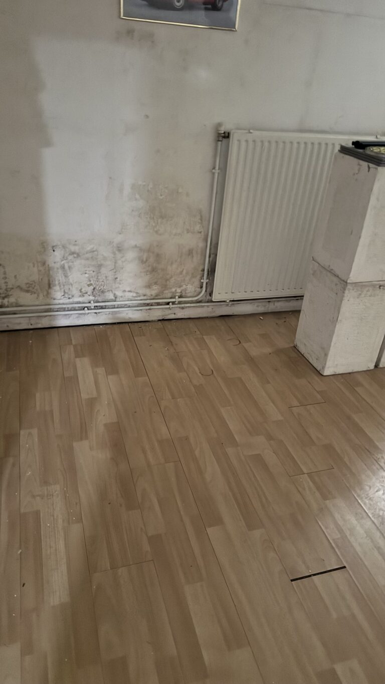 Un mur et le sol endommagés par un dégât des eaux.